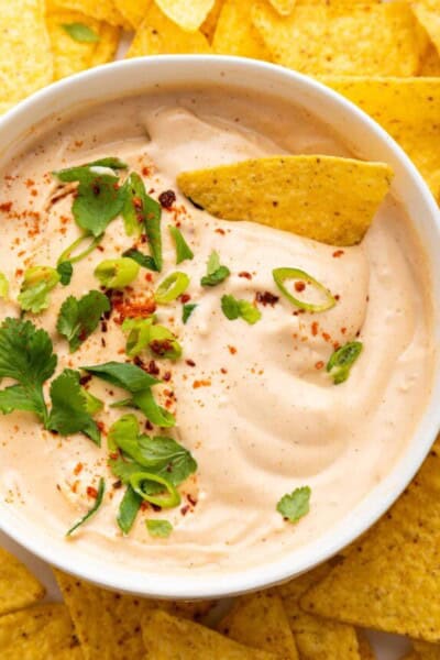 Overhead view of vegan queso in bowl surrounded by tortilla chips