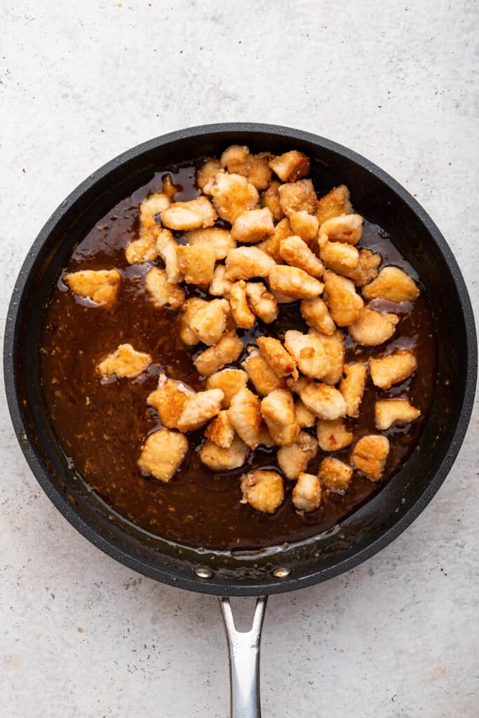 Overhead view of honey sriracha chicken in skillet with sticky sauce