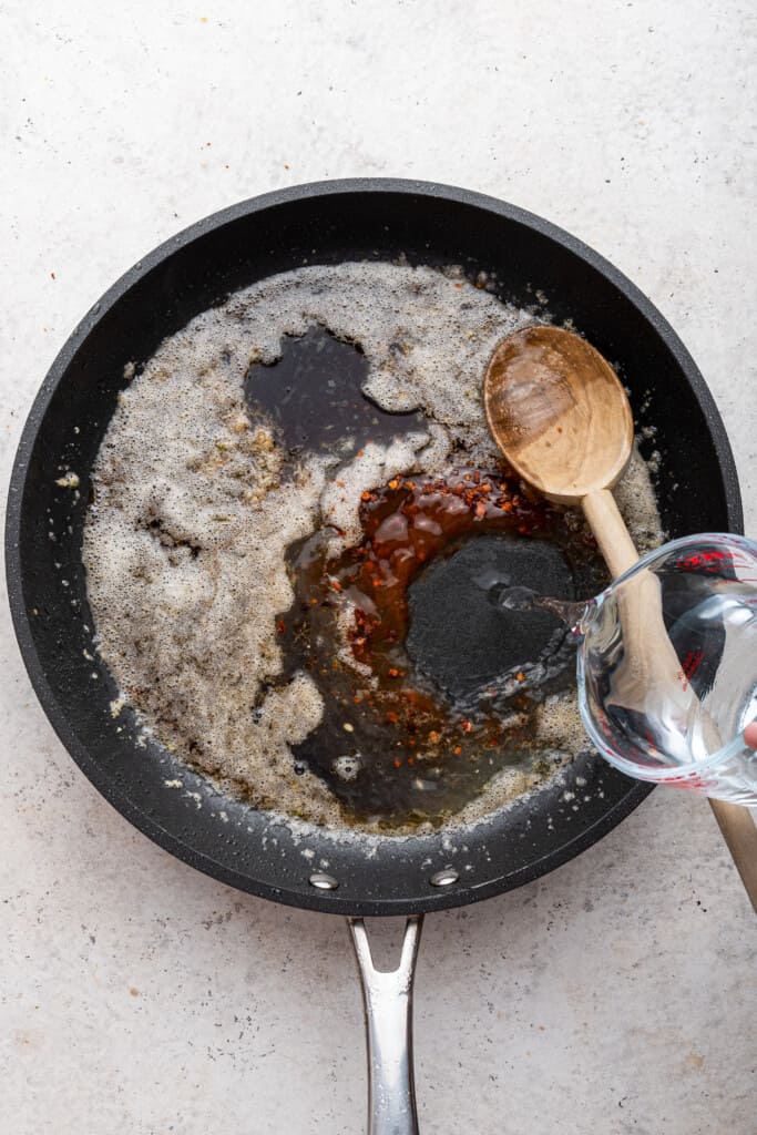 ریختن آب در تابه برای سس برای مرغ سریراچای عسلی