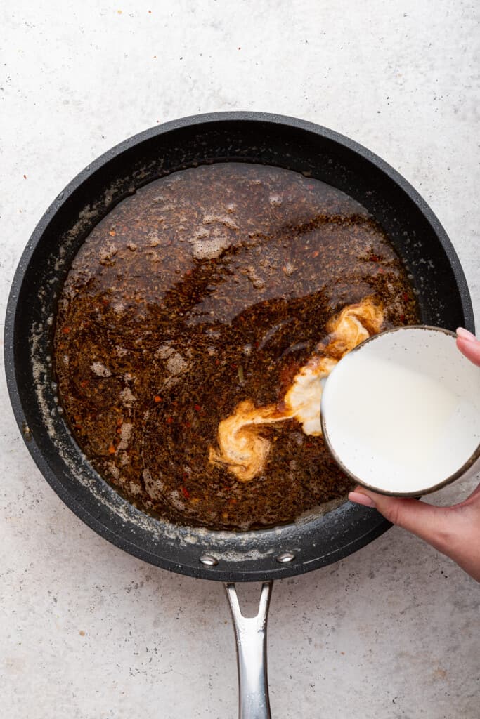 Pouring cornstarch slurry into pan of sauce for chicken