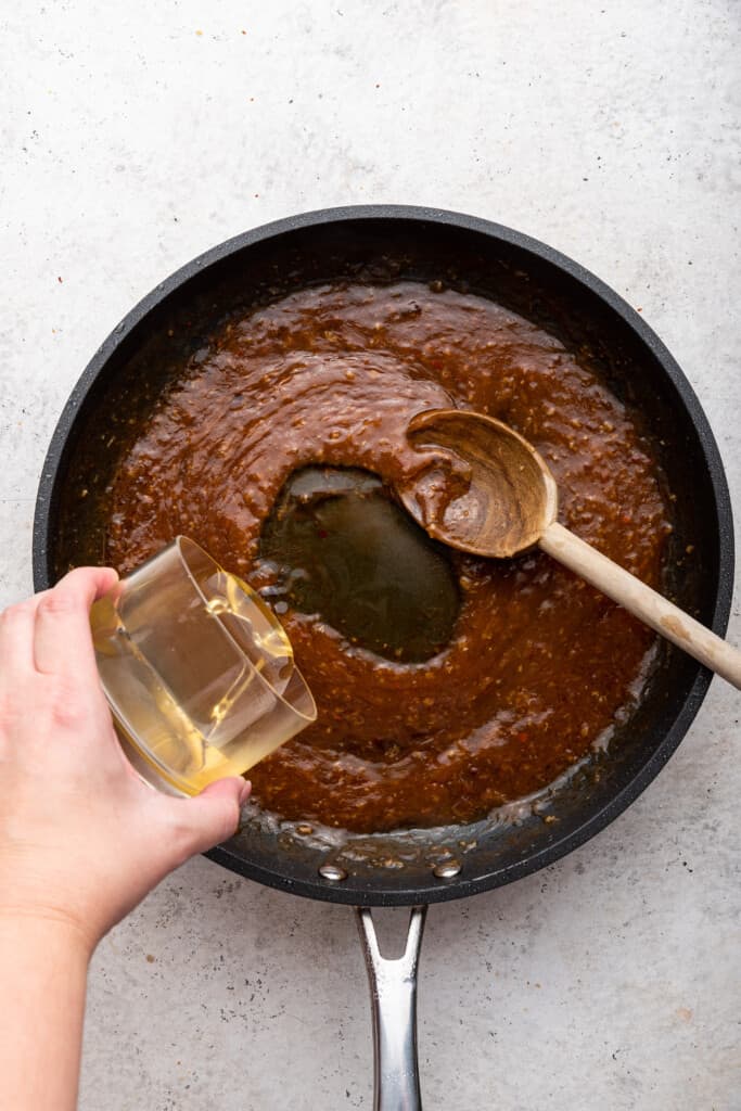 Pouring honey into pan of sauce for chicken