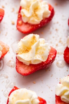 Deviled strawberries topped with whipped cream, graham cracker crumbs, and honey
