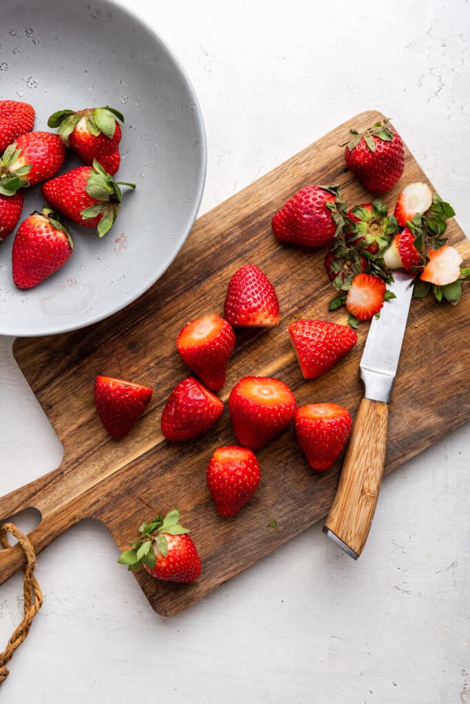 Overhead view of strawberries in bowl and on cutting board with knife