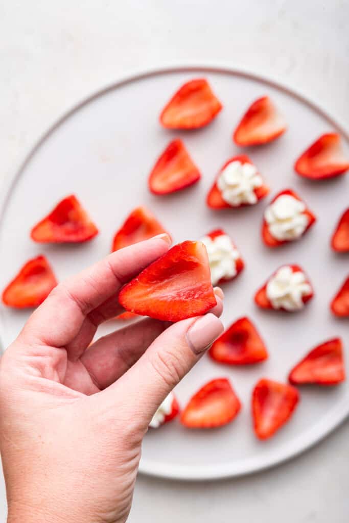 Hand holding halved strawberry with core scooped out
