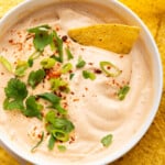 Overhead view of vegan queso in bowl surrounded by tortilla chips