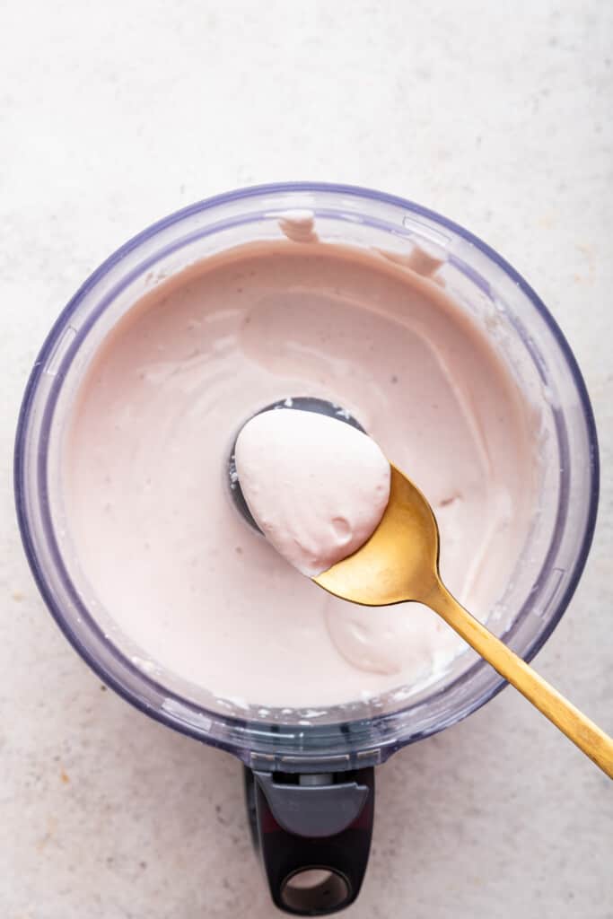Spoonful of whipped cottage cheese held over food processor