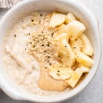 Overhead view of baby oatmeal with nut butter, hemp seed, and banana