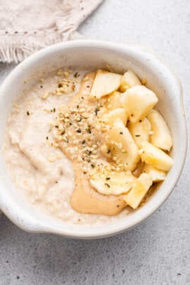 Overhead view of baby oatmeal with nut butter, hemp seed, and banana