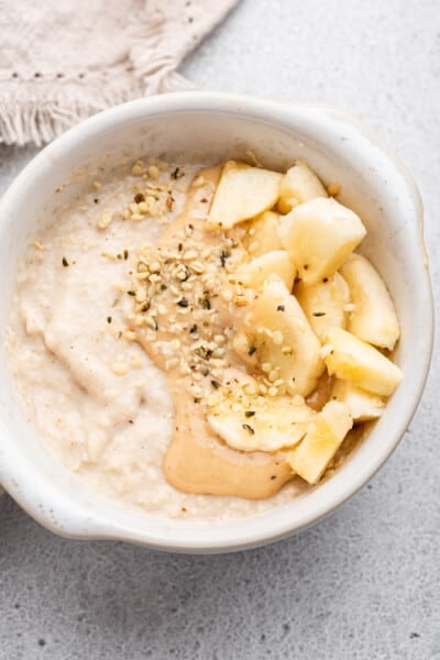 Overhead view of baby oatmeal with nut butter, hemp seed, and banana