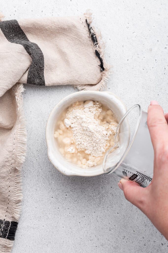 Pouring water into bowl of oat flour