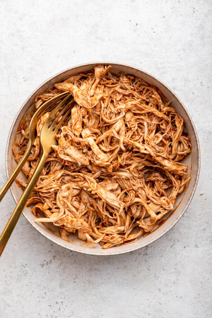 Shredded BBQ chicken in bowl with two forks