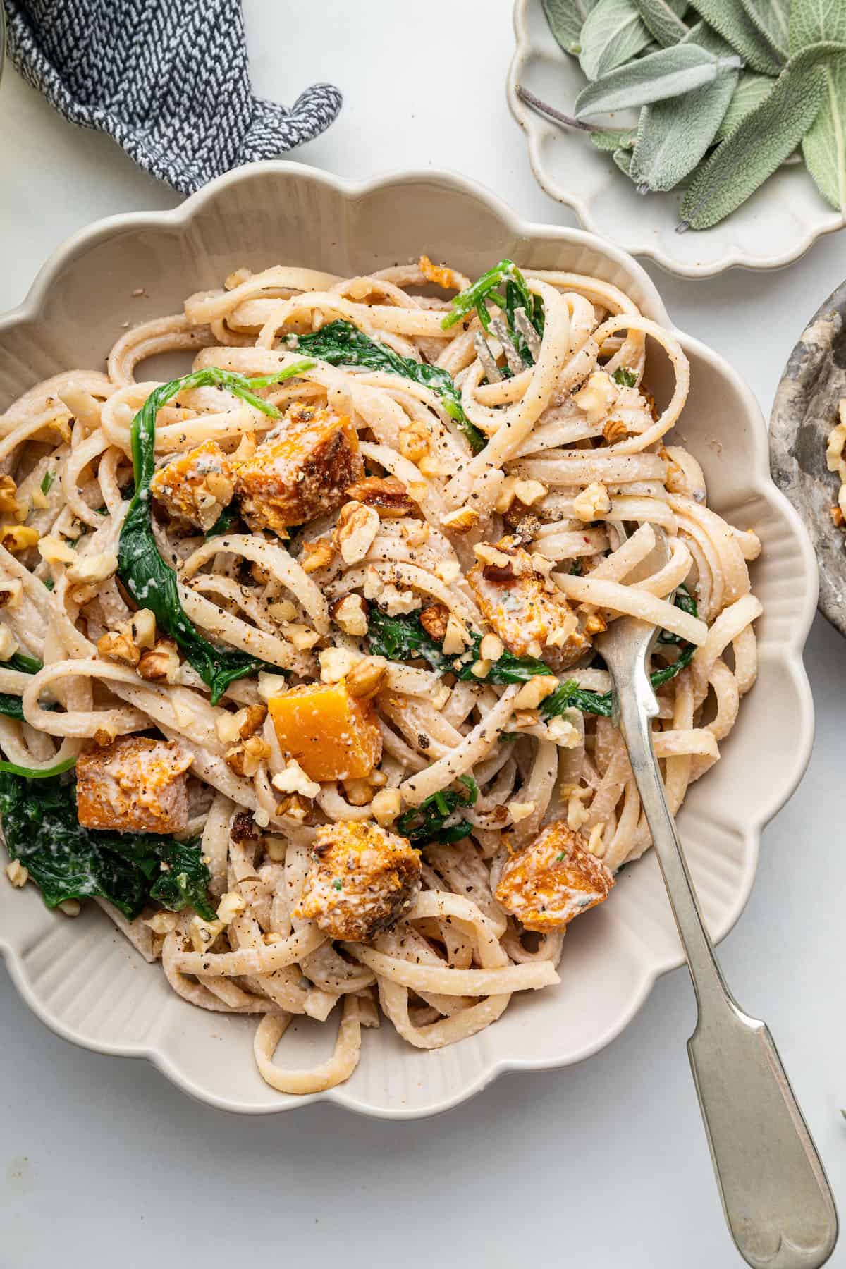This walnut pasta recipe is made with roasted butternut squash, spinach and the most delicious vegan cream sauce. An easy meatless dinner! Bowl of creamy walnut pasta with butternut squash