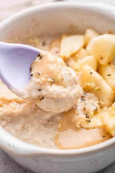 Spoonful of baby oatmeal held over bowl