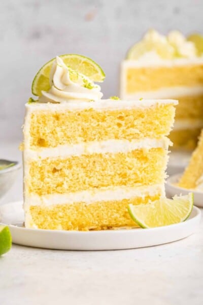 Slice of key lime cake on plate with lime slices