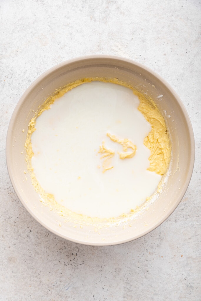 Overhead view of milk added to mixing bowl of cake batter