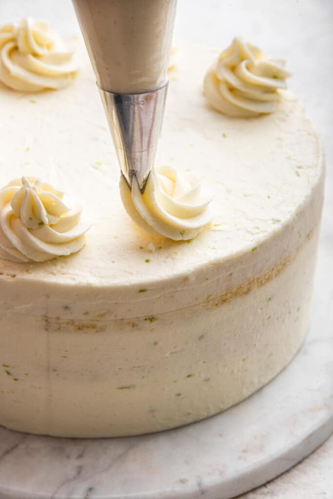 Piping frosting onto key lime cake