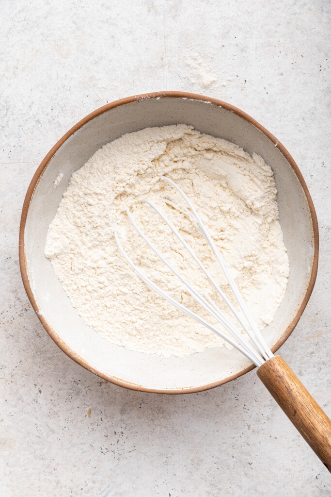 Overhead view of dry ingredients for cake in mixing bowl with whisk