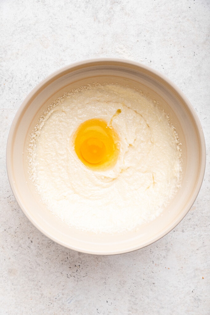 Overhead view of egg added to wet ingredients for cake