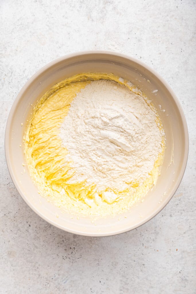 Overhead view of dry ingredients added to mixing bowl of cake batter