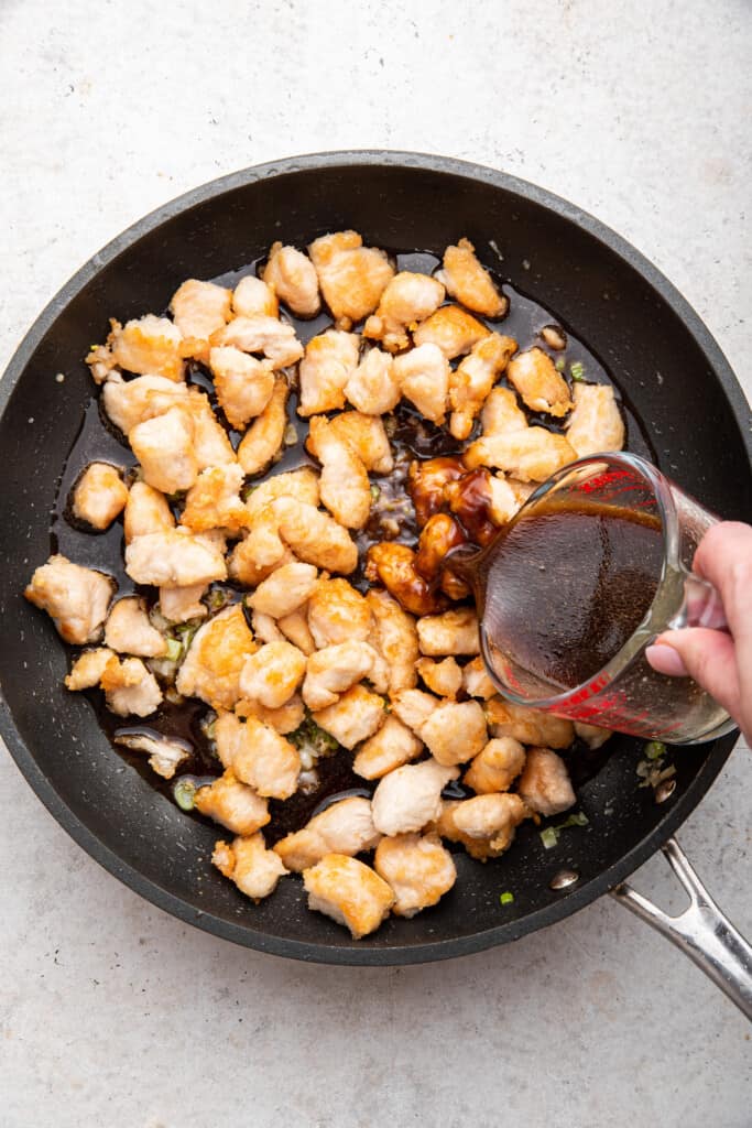 Pouring sauce into pan of chicken