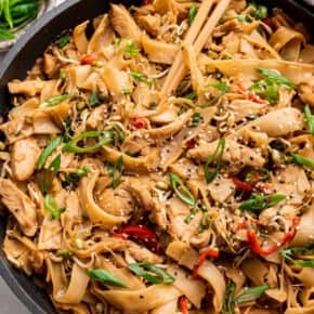 Overhead view of chicken chow fun in serving dish with chopsticks