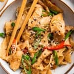 Overhead view of chicken chow fun in bowl with chopsticks