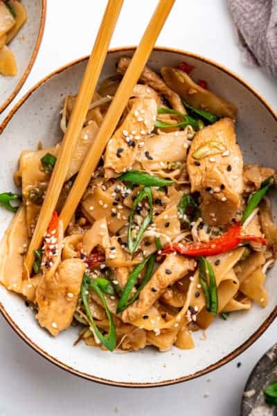 Overhead view of chicken chow fun in bowl with chopsticks