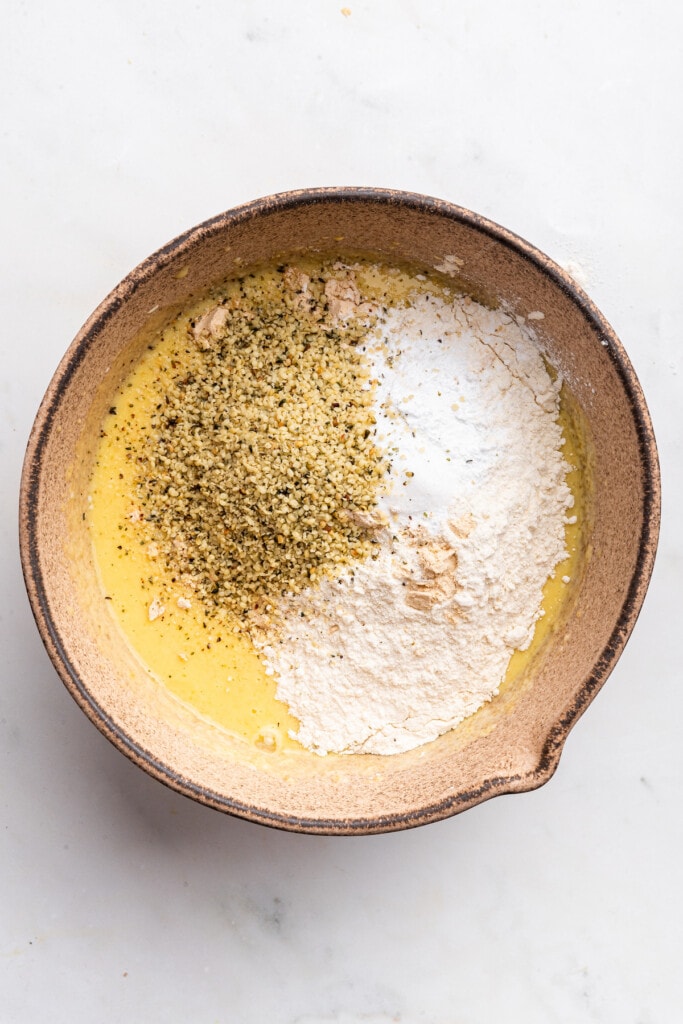 Overhead view of dry ingredients added to bowl of wet ingredients
