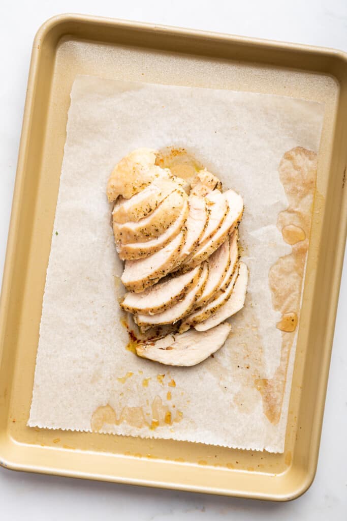 Sliced roasted chicken on sheet pan