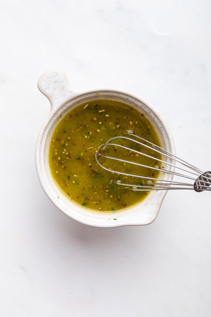 Whisking small bowl of dressing for Jennifer Aniston salad