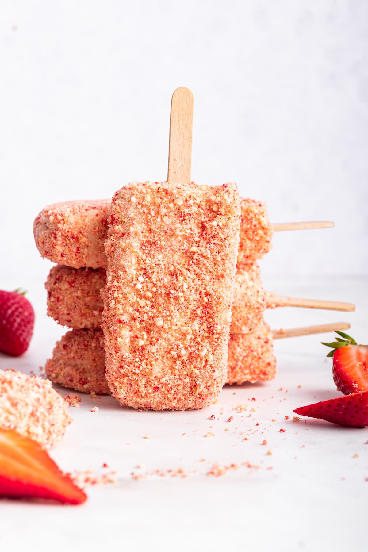 Homemade strawberry shortcake ice cream bars stacked, with one leaning against the rest