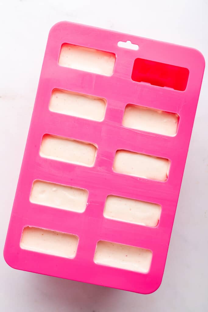 Overhead view of strawberry shortcake ice cream bars filling in popsicle mold