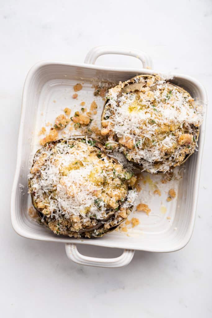 Overhead view of stuffed artichokes in baking dish before baking