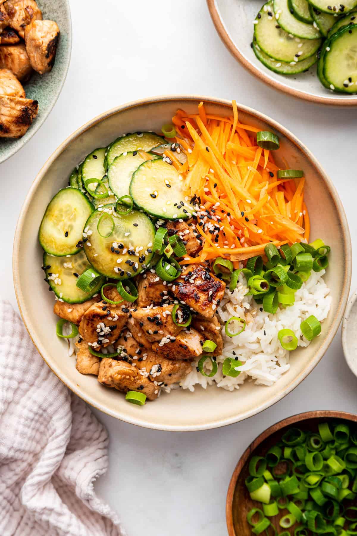 Salmon bowls are a healthy weeknight dinner that pairs flaky baked salmon with rice, cucumber salad, and toppings. So easy and delicious! Overhead view of salmon bowl with cucumber, rice, and carrots
