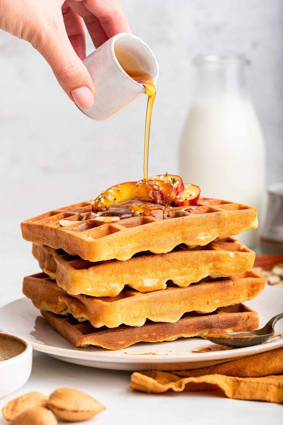 With crispy edges and a fluffy interior, these protein waffles are just as delicious as the original, but they pack in 11 grams of protein! Pouring maple syrup onto stack of high protein waffles