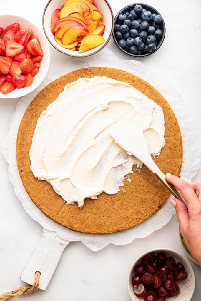 Spreading frosting onto fruit pizza