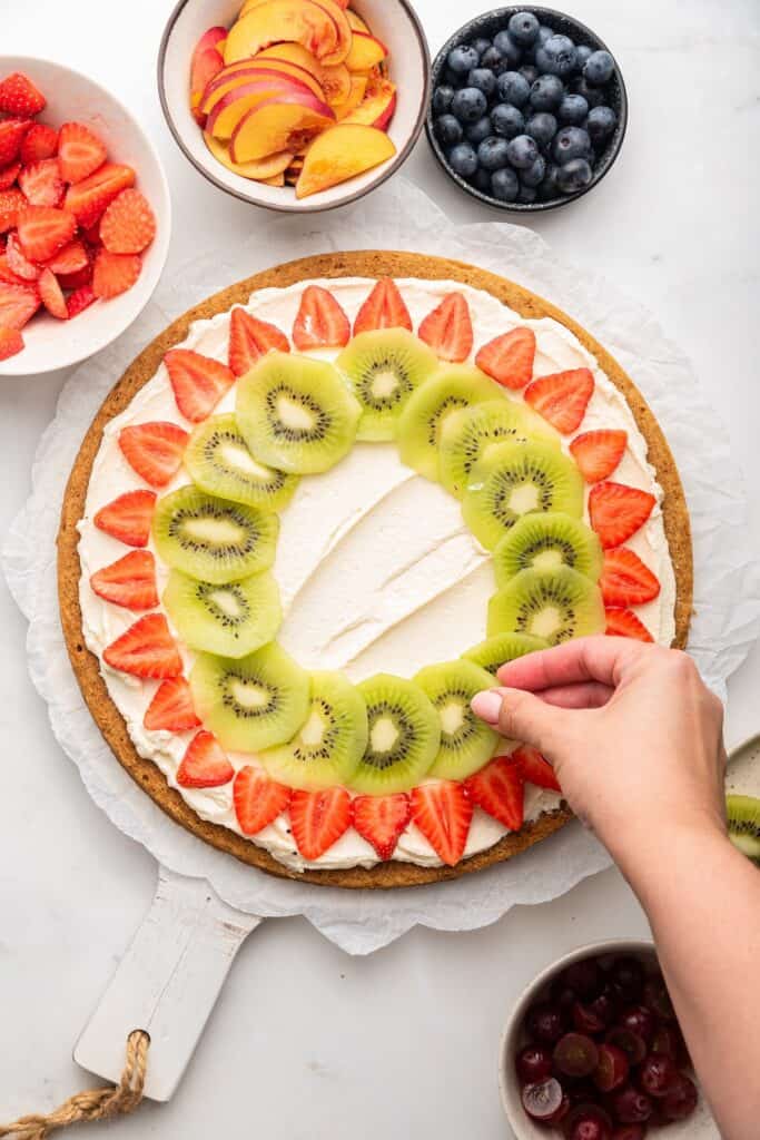 Arranging fruit on fruit pizza