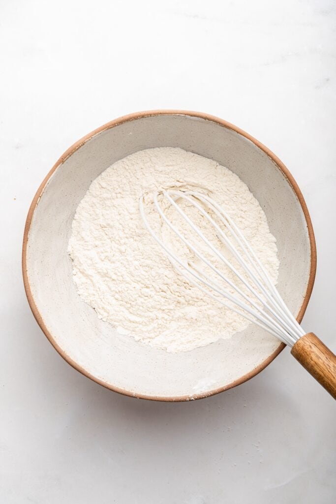 Overhead view of dry ingredients in bowl with whisk