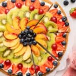 Overhead view of partially sliced fruit pizza