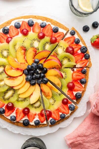 Overhead view of partially sliced fruit pizza