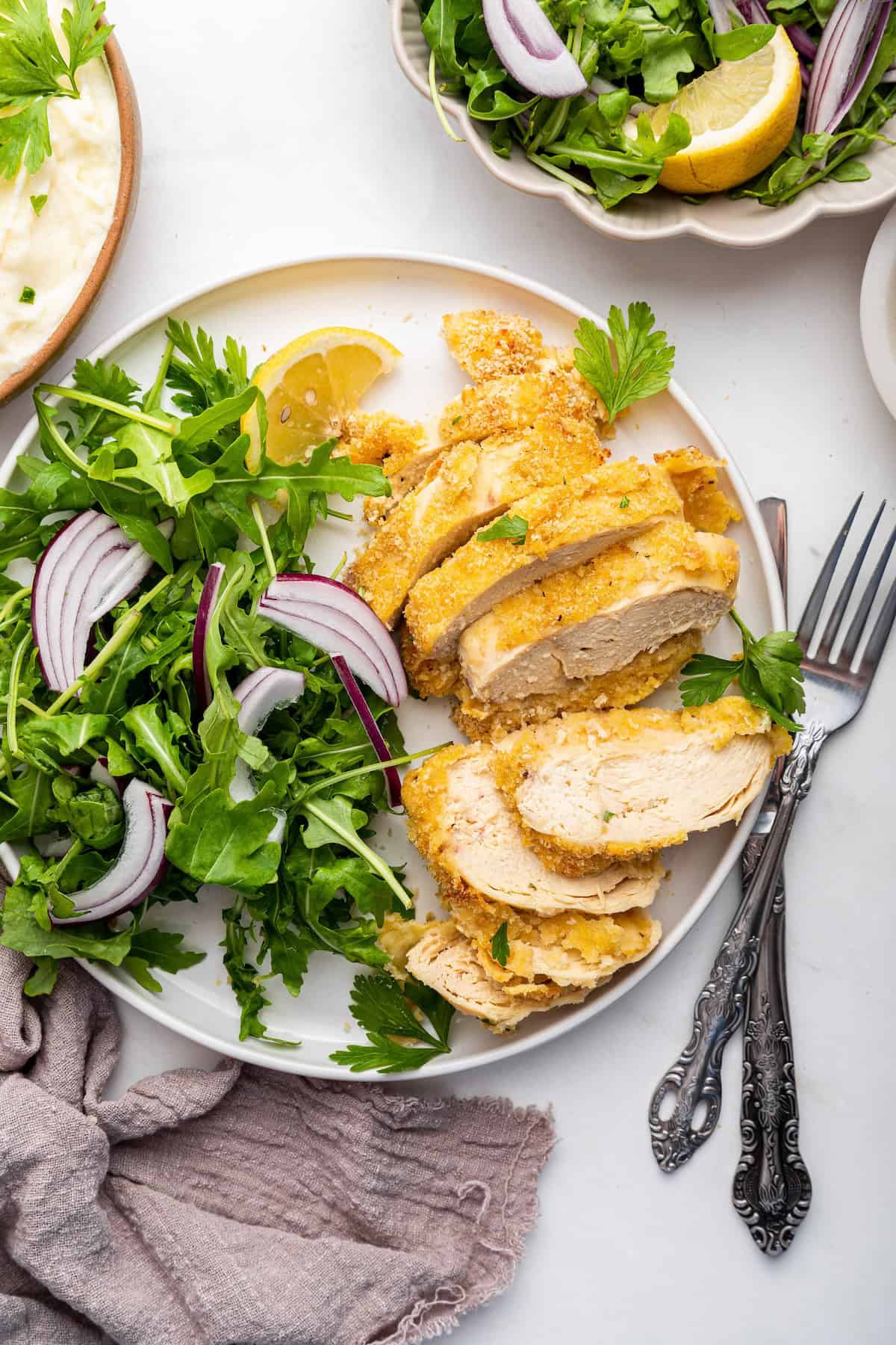 Overhead view of sliced garlic Parmesan chicken on plate with salad