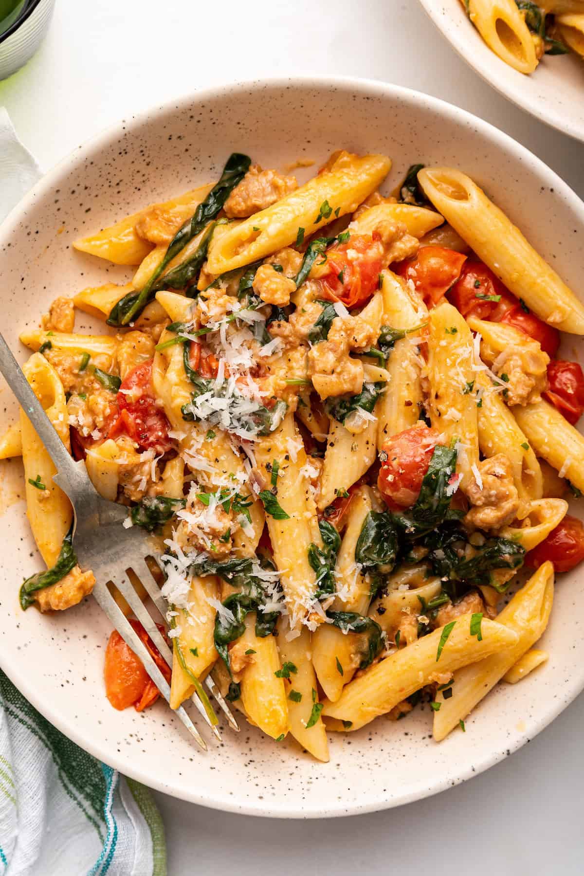 This easy sausage pasta recipe pairs hearty Italian sausage with cherry tomatoes, spinach, and plenty of garlic and Parmesan for big flavor! Bowl of sausage pasta with spinach and cherry tomatoes
