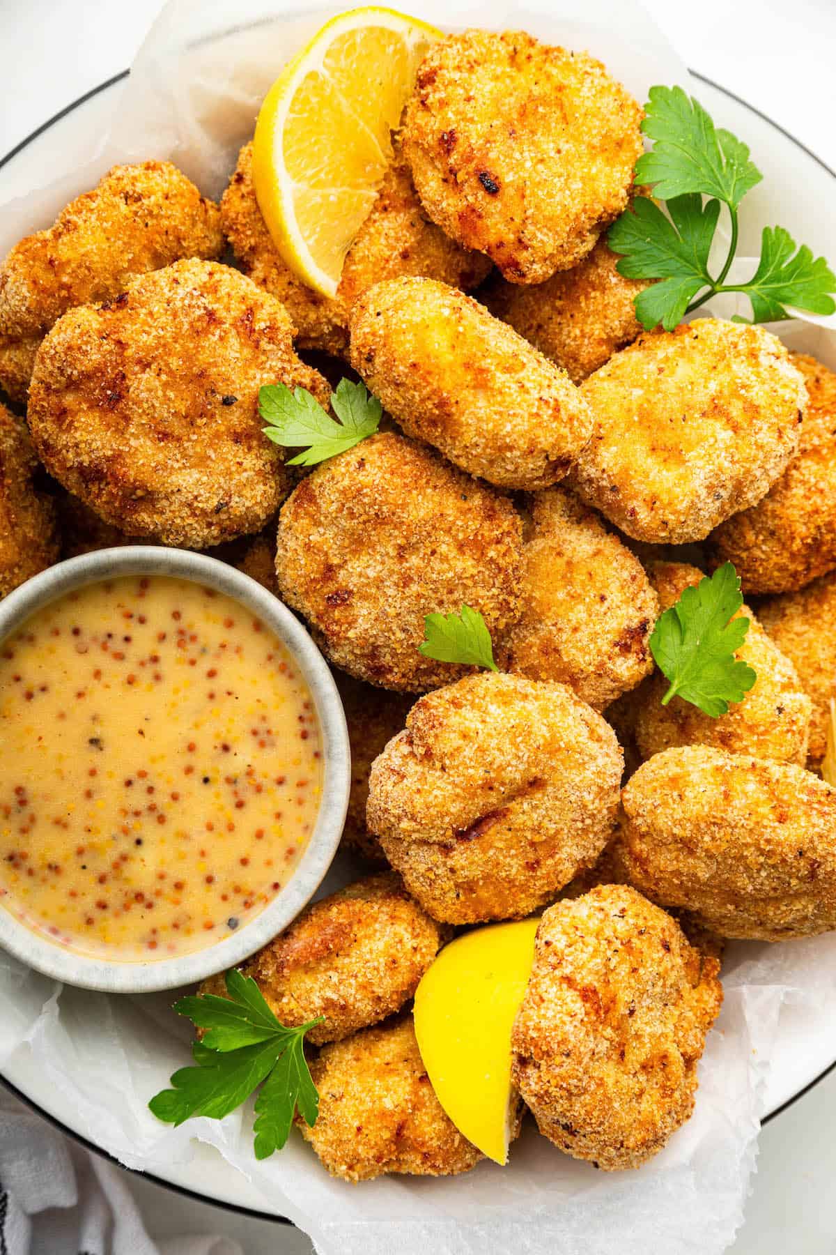 These homemade chicken nuggets are made in the air fryer, so they're crispy without being greasy. An easy recipe your kids will love! Plate of homemade chicken nuggets with dipping sauce