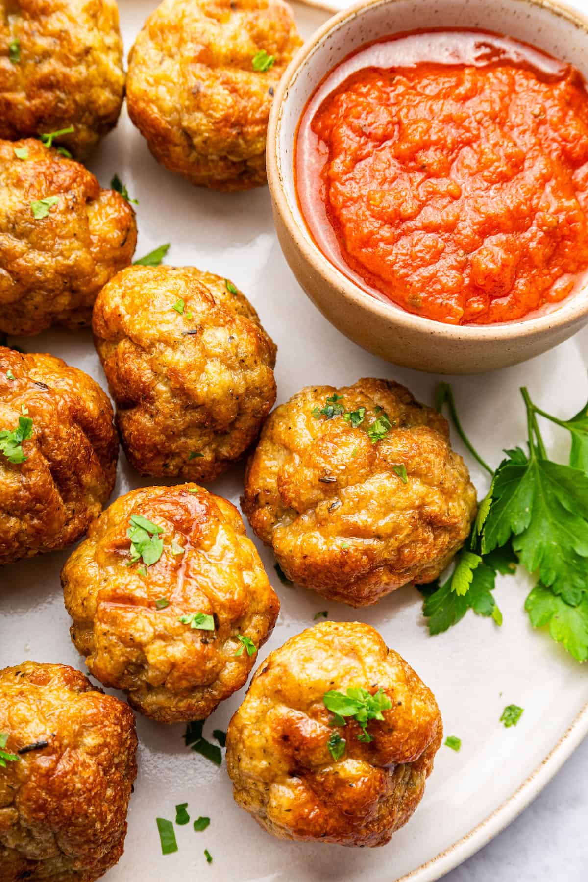 Crispy air fryer turkey meatballs on plate with bowl of sauce