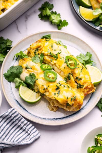 Two green chicken enchiladas on plate
