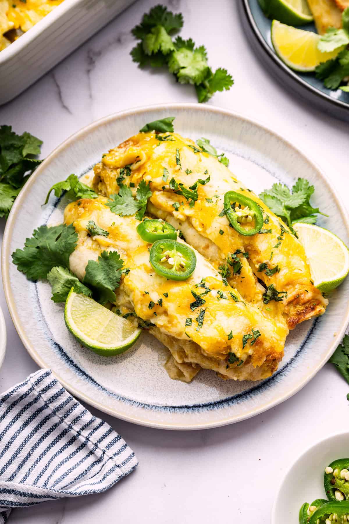 Lots of cheese, zesty enchilada sauce and protein-packed chicken and beans make these green chicken enchiladas satisfying and delicious! Two green chicken enchiladas on plate