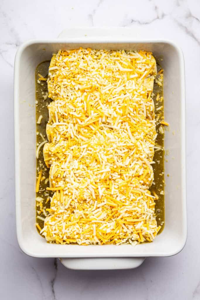 Cheese added to pan of enchiladas before baking