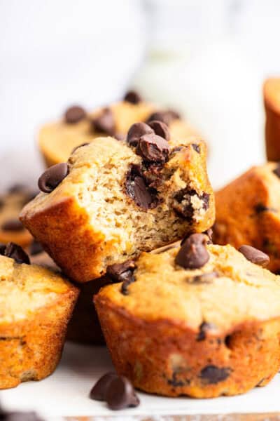 Pile of banana protein muffins with one bitten to show moist texture