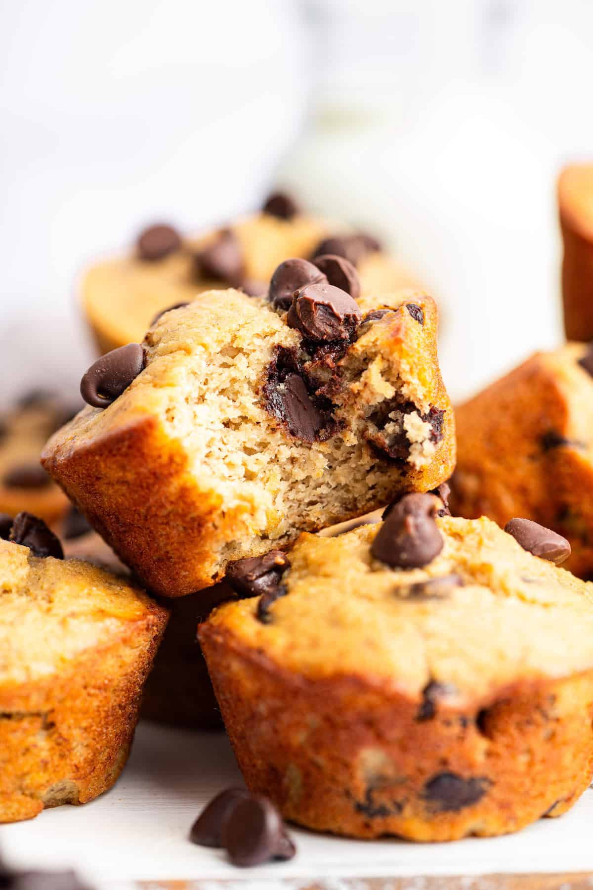 These banana protein muffins are packed with protein and natural sweetness from ripe bananas. They're a great grab-and-go breakfast or snack! Pile of banana protein muffins with one bitten to show moist texture