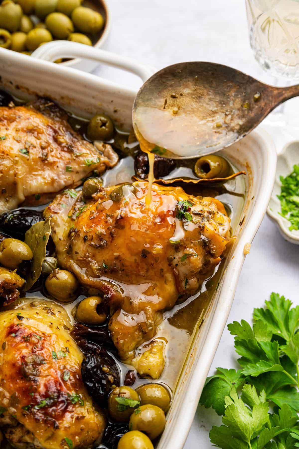 Drizzling sauce over chicken marbella in pan